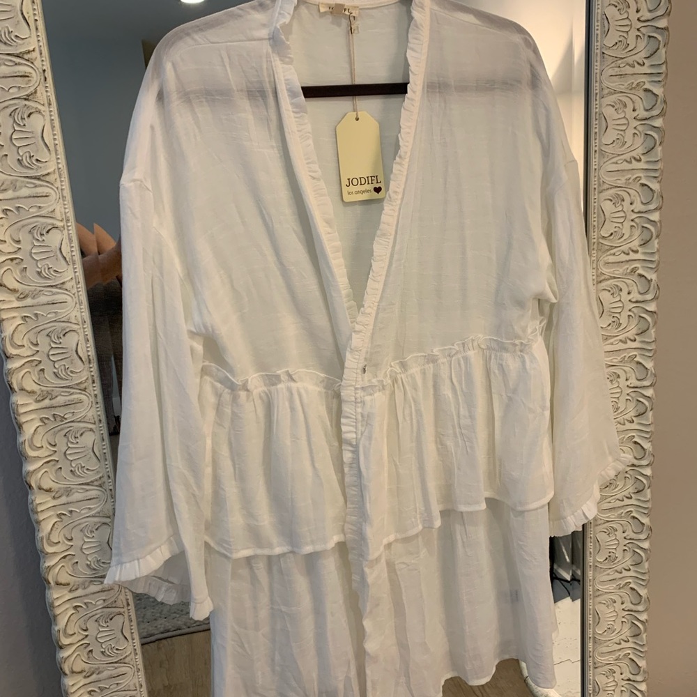 White tunic opens in front. Rufgles on trim. Could be bathing cover or blouse.